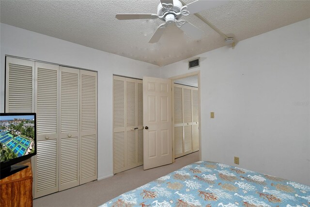601 Islamorada Blvd Unit 24B, Punta Gorda, FL 33955 - bedroom featuring multiple closets, carpet floors, a textured ceiling, and a ceiling fan