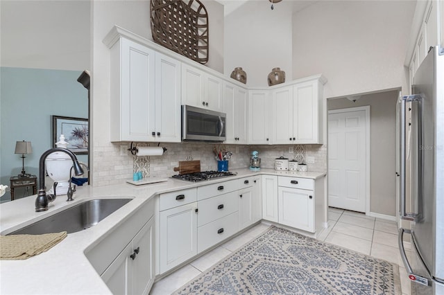 4443 Abcor Rd, North Port, FL 34286 - kitchen featuring appliances with stainless steel finishes, backsplash, light tile patterned flooring, white cabinetry, and a high ceiling
