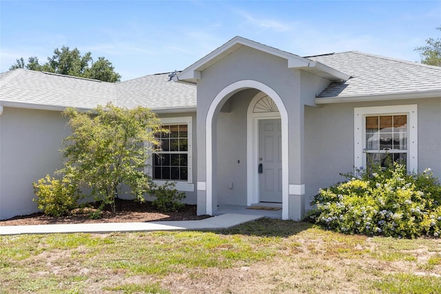 3886 Cincinnati St, North Port, FL 34286 - entrance to property featuring roof with shingles, stucco siding, and a lawn