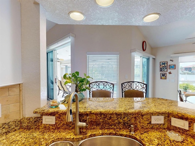 3518 Terin Ct, Punta Gorda, FL 33950 - kitchen with vaulted ceiling, a sink, stone counters, and a textured ceiling