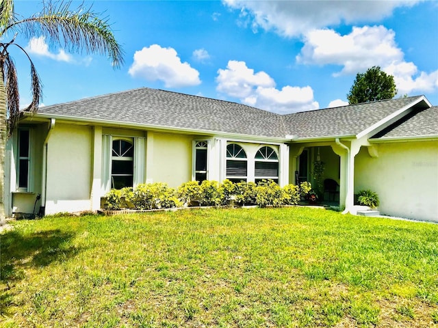 1017 Guild St, Port Charlotte, FL 33952 - back of property with stucco siding, a yard, and roof with shingles