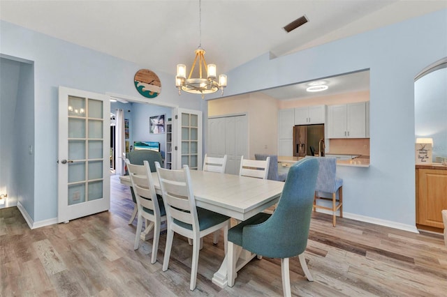 206 Gondola Park Dr Unit 206, Venice, FL 34292 - dining area featuring french doors, a chandelier, lofted ceiling, light wood-type flooring, and baseboards