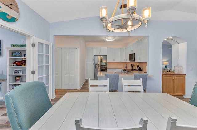 206 Gondola Park Dr Unit 206, Venice, FL 34292 - dining area with lofted ceiling, a chandelier, wood finished floors, and arched walkways