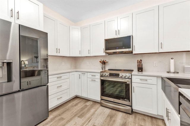 206 Gondola Park Dr Unit 206, Venice, FL 34292 - kitchen with appliances with stainless steel finishes, light countertops, decorative backsplash, light wood-style flooring, and white cabinetry