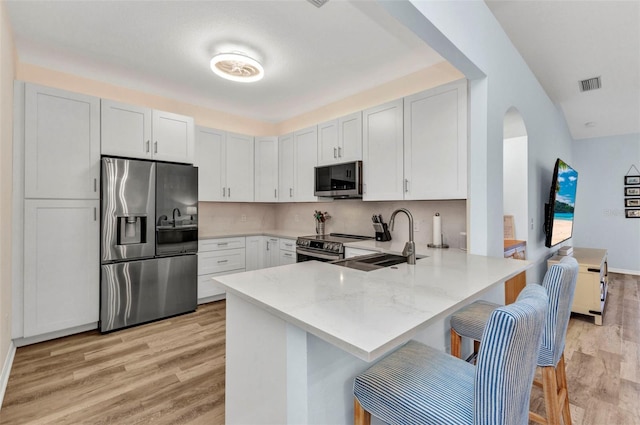 206 Gondola Park Dr Unit 206, Venice, FL 34292 - kitchen with appliances with stainless steel finishes, a sink, a peninsula, light wood-style flooring, and arched walkways
