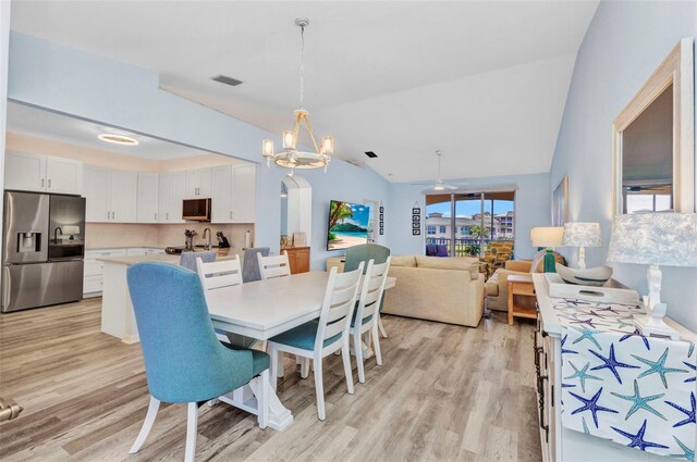 206 Gondola Park Dr Unit 206, Venice, FL 34292 - dining area with light wood-style flooring, a chandelier, vaulted ceiling, and arched walkways