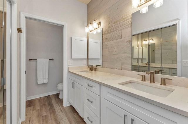 206 Gondola Park Dr Unit 206, Venice, FL 34292 - full bath with double vanity, toilet, wood finished floors, baseboards, and wooden walls