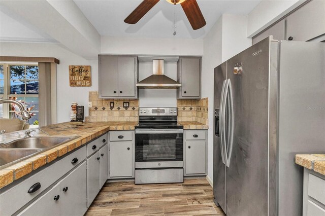 2626 Auburn Blvd, Port Charlotte, FL 33948 - kitchen with stainless steel appliances, wall chimney exhaust hood, a sink, ceiling fan, and light wood-style floors