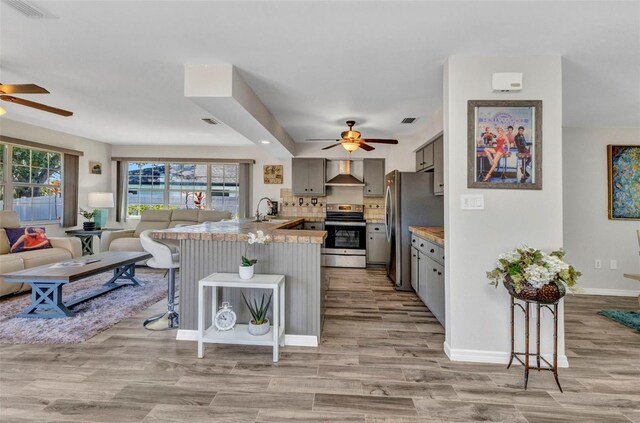 2626 Auburn Blvd, Port Charlotte, FL 33948 - kitchen featuring ceiling fan, stainless steel appliances, wall chimney range hood, and a peninsula