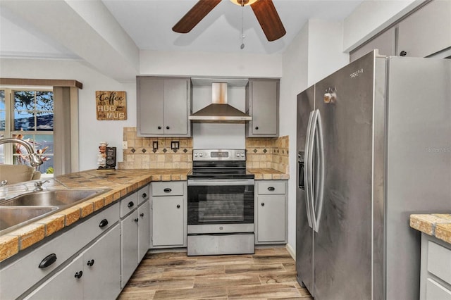2626 Auburn Blvd, Port Charlotte, FL 33948 - kitchen with stainless steel appliances, wall chimney range hood, ceiling fan, light wood-type flooring, and decorative backsplash