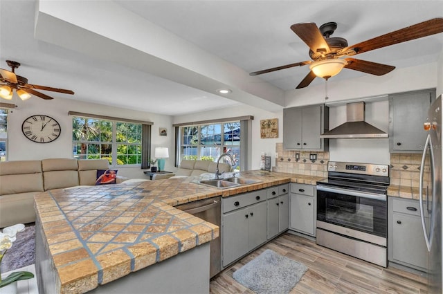 2626 Auburn Blvd, Port Charlotte, FL 33948 - kitchen featuring wall chimney exhaust hood, appliances with stainless steel finishes, ceiling fan, gray cabinetry, and a peninsula