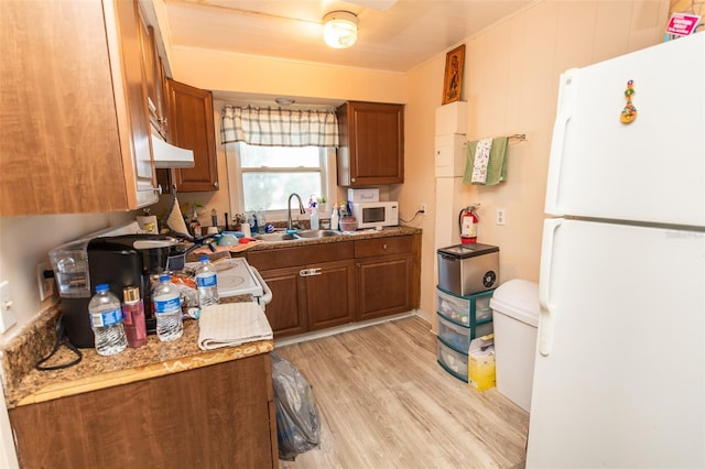 114 N Dade Ave, Arcadia, FL 34266 - kitchen with white appliances, brown cabinets, light wood-type flooring, and a sink
