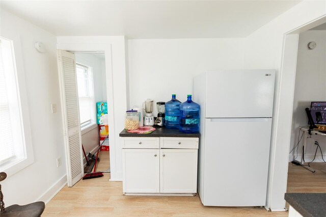 114 N Dade Ave, Arcadia, FL 34266 - kitchen with freestanding refrigerator, dark countertops, light wood-style floors, white cabinetry, and baseboards
