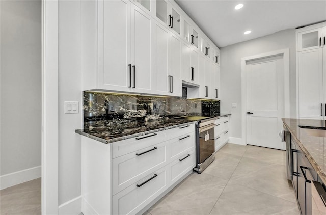 15 Tournament Rd, Rotonda West, FL 33947 - kitchen with decorative backsplash, recessed lighting, dark stone countertops, glass insert cabinets, and white cabinets