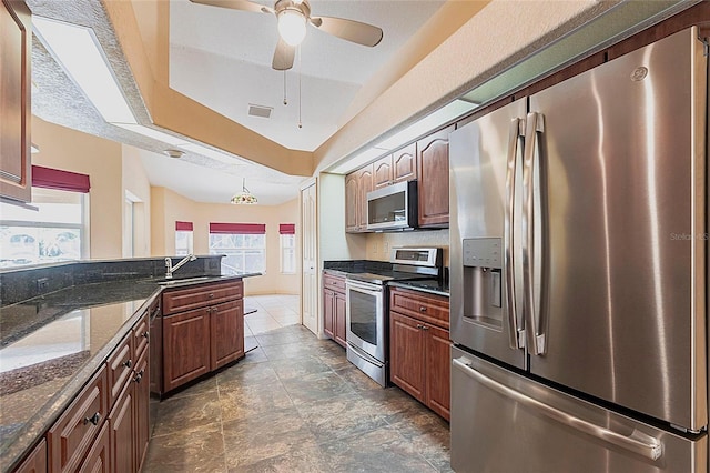 25538 Rampart Blvd, Punta Gorda, FL 33983 - kitchen with stainless steel appliances, a sink, a ceiling fan, dark stone counters, and decorative light fixtures