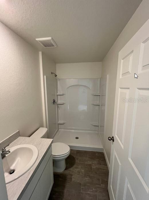 4310 Alvin St, Hastings, FL 32145 - bathroom with a stall shower, toilet, vanity, and a textured ceiling