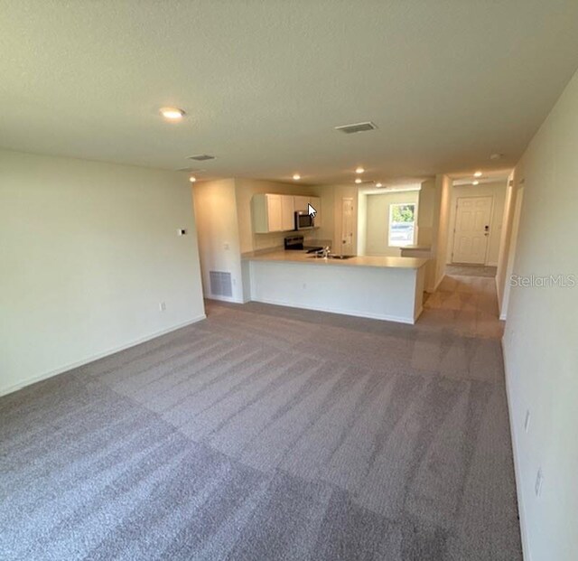 5 Princess Luise Ln, Palm Coast, FL 32164 - unfurnished living room with light carpet, recessed lighting, baseboards, and a textured ceiling