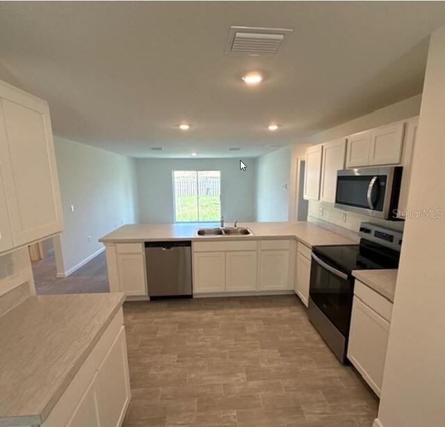 5 Princess Luise Ln, Palm Coast, FL 32164 - kitchen with stainless steel appliances, a peninsula, a sink, white cabinets, and recessed lighting
