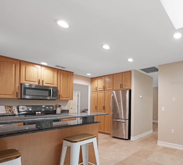1039 Marlene St, Port Charlotte, FL 33952 - kitchen with appliances with stainless steel finishes, a kitchen breakfast bar, dark stone counters, baseboards, and recessed lighting