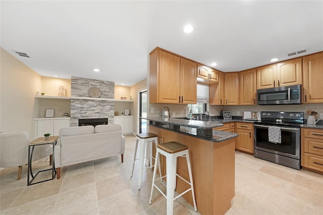 1039 Marlene St, Port Charlotte, FL 33952 - kitchen featuring appliances with stainless steel finishes, a kitchen breakfast bar, a sink, a peninsula, and dark stone counters
