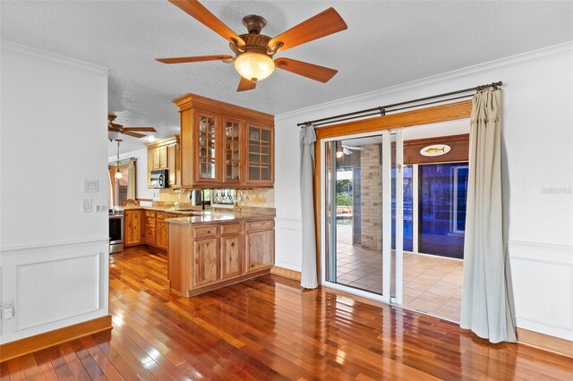 4317 Mccullough St, Port Charlotte, FL 33948 - kitchen featuring a peninsula, ceiling fan, crown molding, stainless steel appliances, and hardwood / wood-style floors