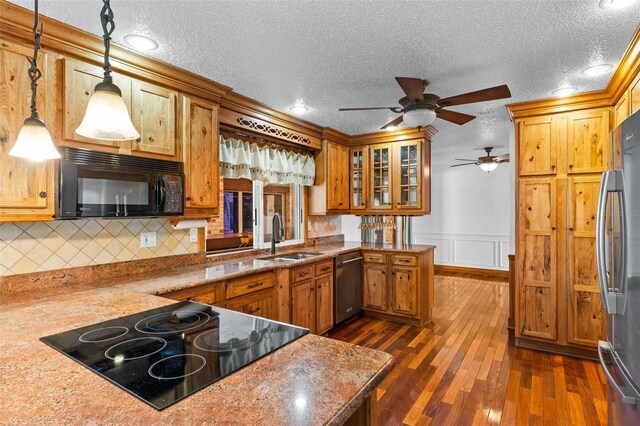 4317 Mccullough St, Port Charlotte, FL 33948 - kitchen with stainless steel appliances, a sink, a textured ceiling, brown cabinets, and a wainscoted wall