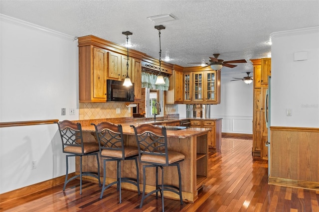 4317 Mccullough St, Port Charlotte, FL 33948 - kitchen with black microwave, brown cabinetry, a peninsula, ceiling fan, and a kitchen bar
