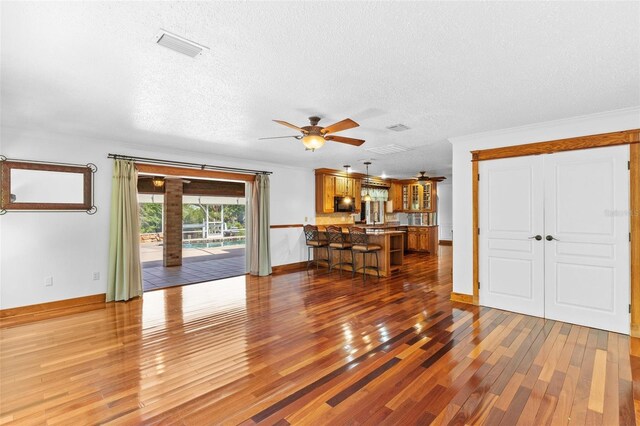 4317 Mccullough St, Port Charlotte, FL 33948 - unfurnished living room with wood finished floors, ceiling fan, a textured ceiling, baseboards, and crown molding