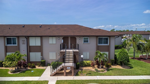 25100 Sandhill Blvd Unit 204, Punta Gorda, FL 33983 - townhome / multi-family property with stucco siding, a front yard, stairway, and a shingled roof