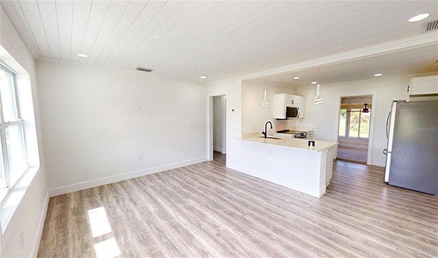 2805 Gussie St, Punta Gorda, FL 33950 - kitchen with stainless steel appliances, a sink, light wood-type flooring, white cabinetry, and light countertops