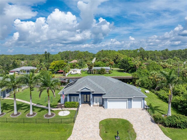 1025 Cheshire St, Port Charlotte, FL 33953 - view of front of property with french doors, an attached garage, driveway, and a forest view