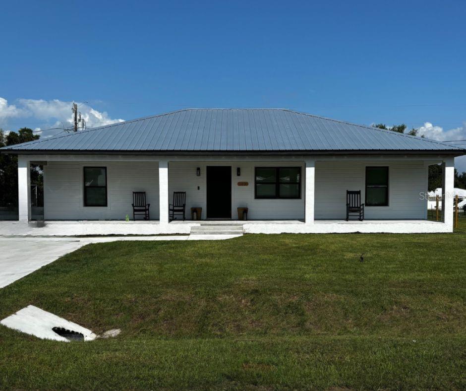 8306 SW Easy St, Arcadia, FL 34269 - rear view of property with covered porch, metal roof, and a lawn