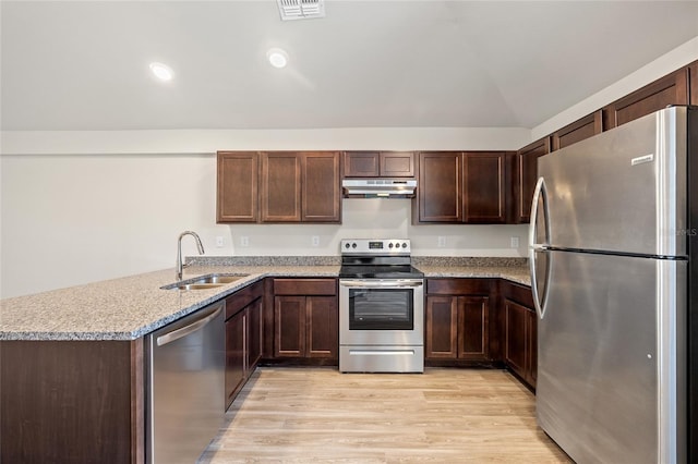 27237 Partin Dr, Punta Gorda, FL 33983 - kitchen with appliances with stainless steel finishes, a sink, under cabinet range hood, light wood-type flooring, and a peninsula