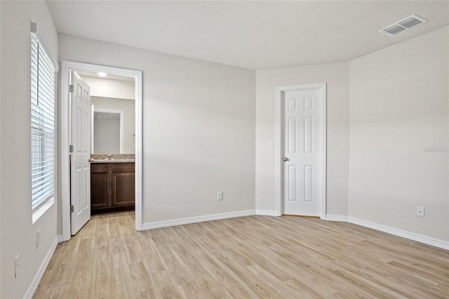 27237 Partin Dr, Punta Gorda, FL 33983 - unfurnished bedroom featuring light wood-style floors, baseboards, and ensuite bath