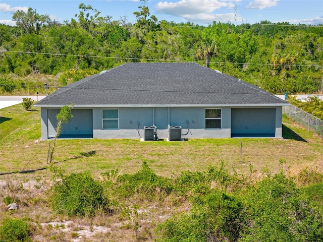 27237 Partin Dr, Punta Gorda, FL 33983 - back of house featuring central AC unit, stucco siding, and a view of trees