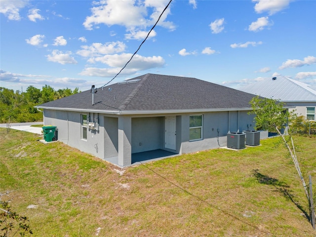 27237 Partin Dr, Punta Gorda, FL 33983 - back of house featuring central air condition unit, a lawn, stucco siding, and a shingled roof