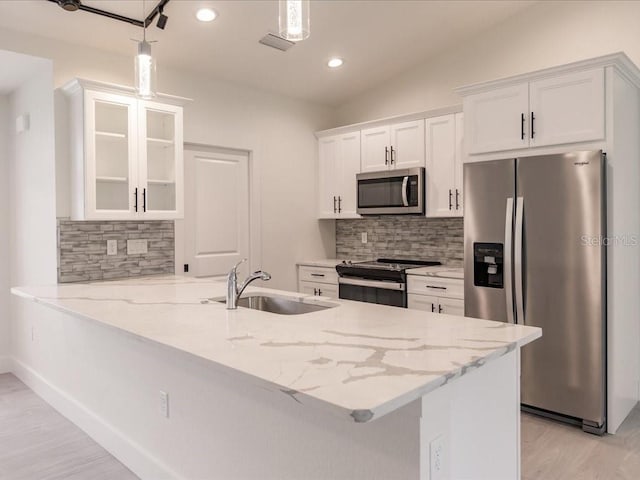 17130 Elder St, Port Charlotte, FL 33954 - kitchen with appliances with stainless steel finishes, a sink, light wood finished floors, white cabinets, and decorative backsplash