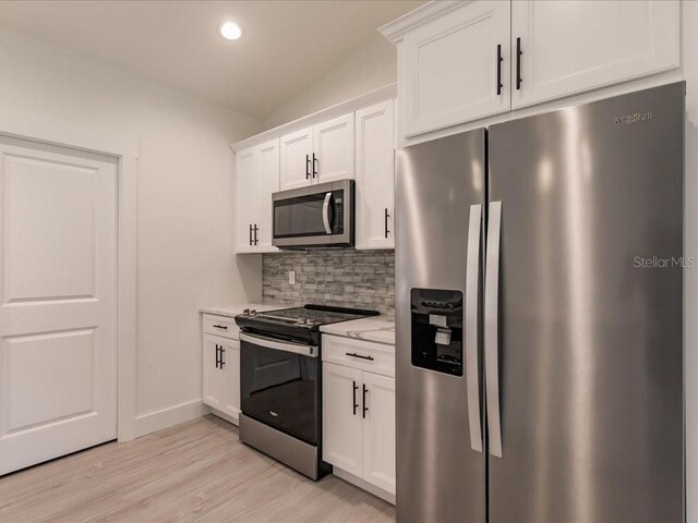 17130 Elder St, Port Charlotte, FL 33954 - kitchen with appliances with stainless steel finishes, decorative backsplash, white cabinets, light wood-style flooring, and recessed lighting