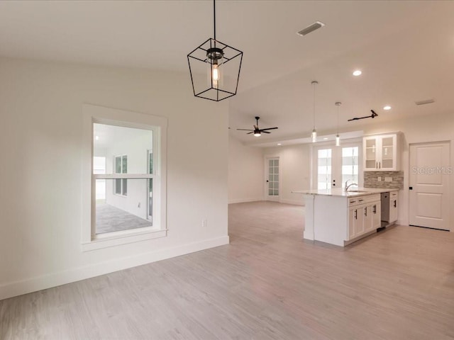 17130 Elder St, Port Charlotte, FL 33954 - kitchen with stainless steel dishwasher, a sink, open floor plan, white cabinets, and baseboards
