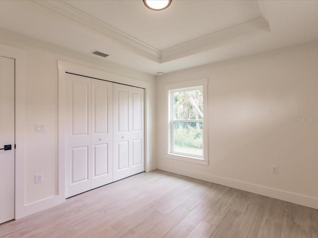 17130 Elder St, Port Charlotte, FL 33954 - unfurnished bedroom featuring a raised ceiling, crown molding, baseboards, light wood finished floors, and a closet