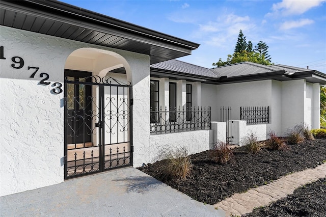 19723 Midway Blvd, Port Charlotte, FL 33948 - view of exterior entry featuring a gate, stucco siding, and metal roof