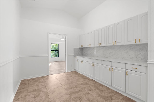19723 Midway Blvd, Port Charlotte, FL 33948 - kitchen with light countertops, backsplash, lofted ceiling, white cabinetry, and baseboards