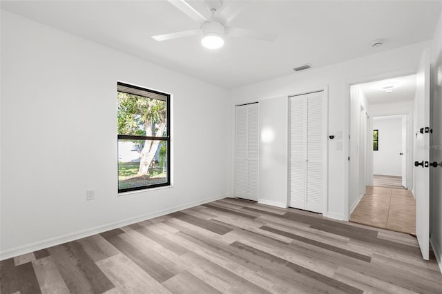 19723 Midway Blvd, Port Charlotte, FL 33948 - unfurnished bedroom with multiple closets, light wood finished floors, and a ceiling fan