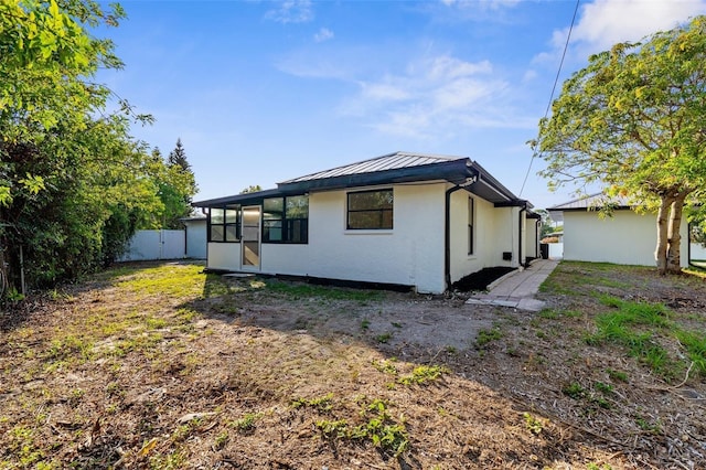 19723 Midway Blvd, Port Charlotte, FL 33948 - rear view of property featuring a sunroom, a standing seam roof, metal roof, and stucco siding