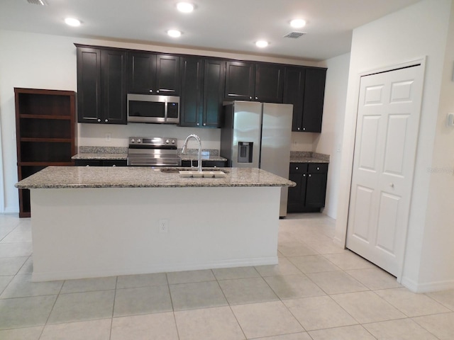 4830 Cazes Ave, North Port, FL 34287 - kitchen with appliances with stainless steel finishes, a sink, a kitchen island with sink, light stone countertops, and dark cabinets