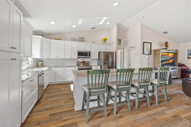16094 Ortega Dr, Punta Gorda, FL 33955 - kitchen with appliances with stainless steel finishes, a sink, a kitchen island, a kitchen breakfast bar, and white cabinetry