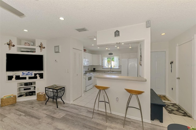 4044 S Salford Blvd, North Port, FL 34287 - kitchen with white appliances, a sink, white cabinetry, a breakfast bar, and a textured ceiling