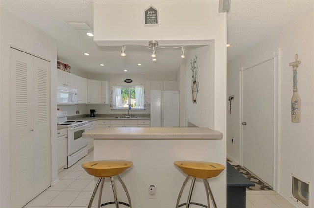 4044 S Salford Blvd, North Port, FL 34287 - kitchen featuring white appliances, a sink, a peninsula, light tile patterned floors, and a breakfast bar area