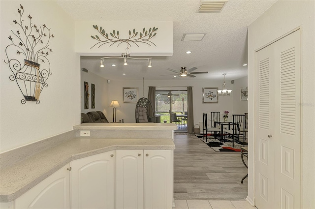 4044 S Salford Blvd, North Port, FL 34287 - kitchen with ceiling fan, a peninsula, light countertops, a textured ceiling, and white cabinets