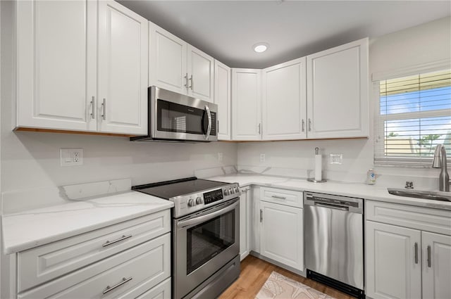 1080 Bal Harbor Blvd Unit 12C, Punta Gorda, FL 33950 - kitchen featuring appliances with stainless steel finishes, a sink, white cabinets, light wood-type flooring, and recessed lighting